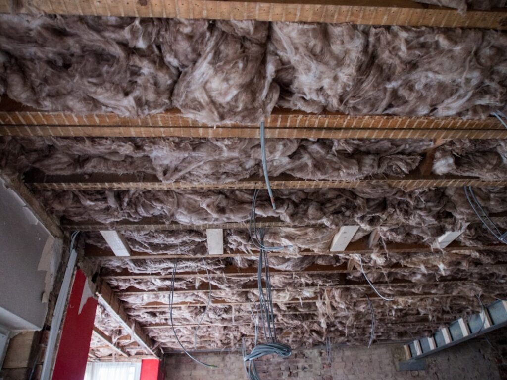 A homeowner inspecting attic insulation for signs of moisture and wear.