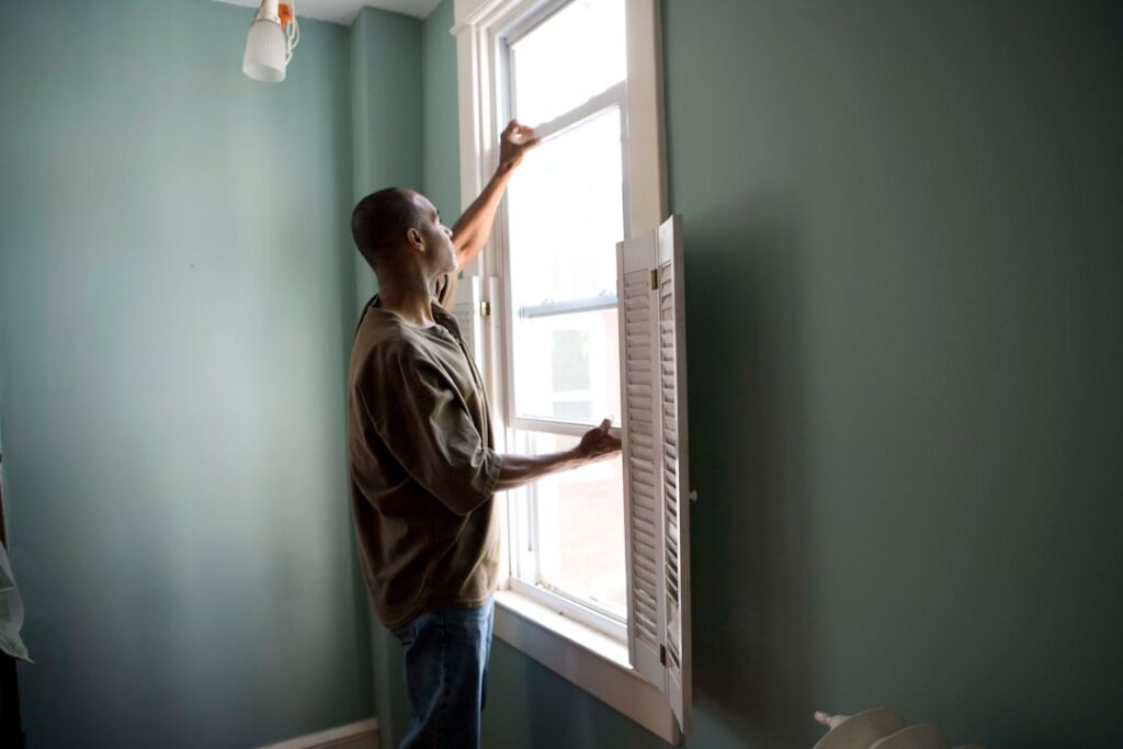A homeowner checking attic insulation with a flashlight on a cold day