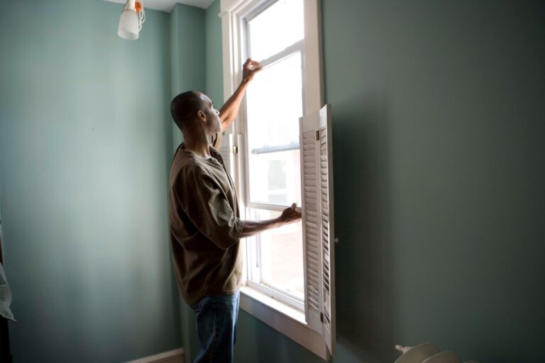 A homeowner checking attic insulation with a flashlight on a cold day