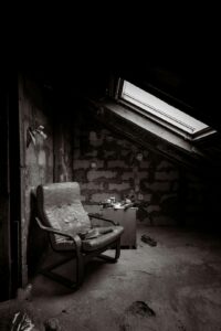 Worker examines evenly installed attic insulation beneath a roof while sunlight enters through the rafters.