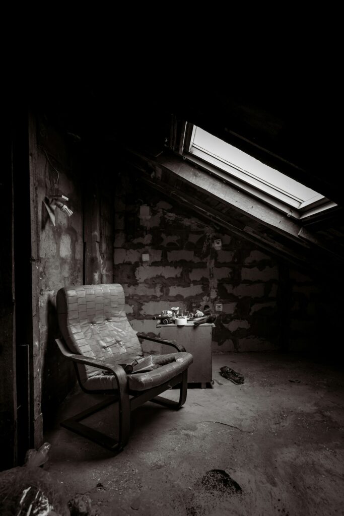 Worker examines evenly installed attic insulation beneath a roof while sunlight enters through the rafters.