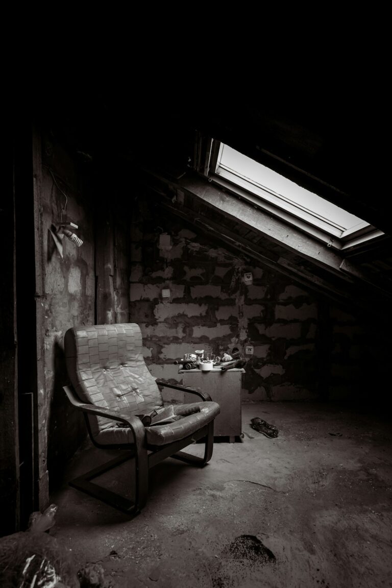 Worker examines evenly installed attic insulation beneath a roof while sunlight enters through the rafters.